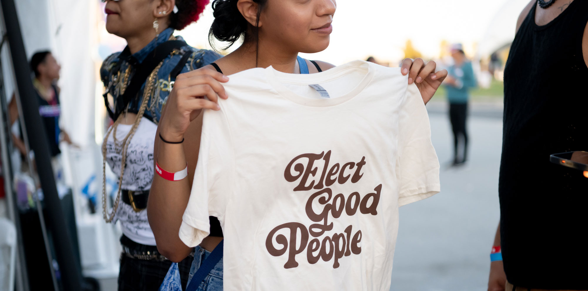 Image of woman holding Elect Good People T-shirt and smiling,