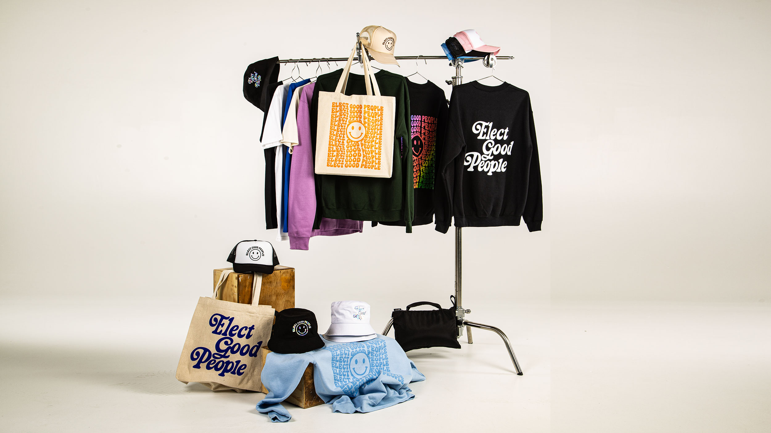 Product shot of Elect Good People merchandise including tote bags, hats, sweatshirts, and T-shirts. 
